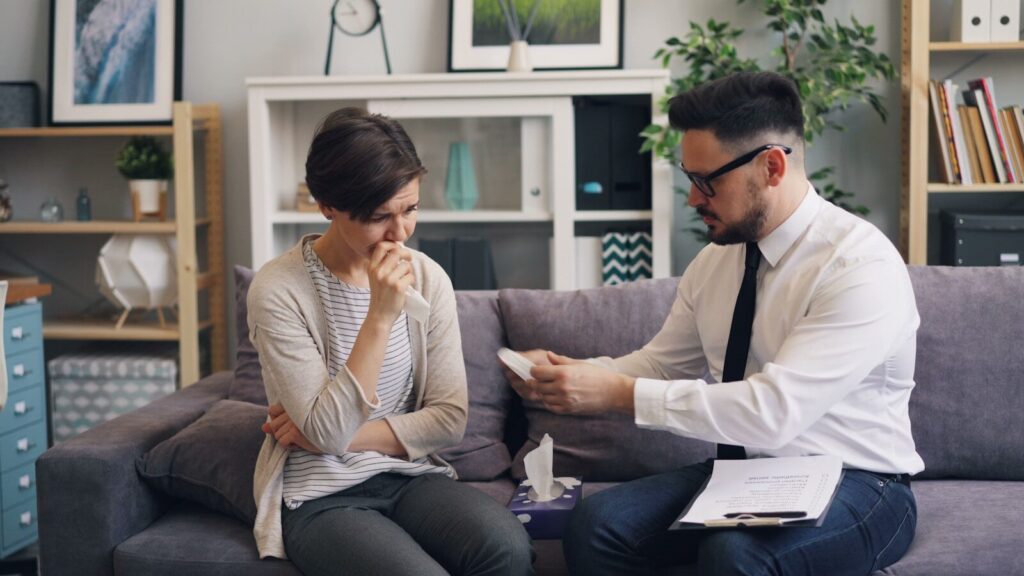 A mental health professional comforts a distressed woman during a counseling session, emphasizing emotional support in a therapeutic setting.